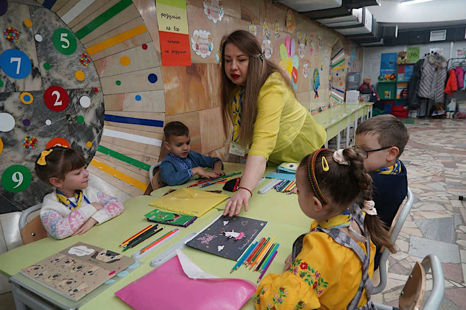 dpatopbilder - Eine Erzieherin verteilt in einem unterirdischen Kindergarten in Charkiw Malbücher und Stifte. Die Verwaltung der ostukrainischen Stadt richtet in U-Bahn-Stationen Kindergärten ein, um die Kinder vor russischen Raketenangriffen zu schützen.  