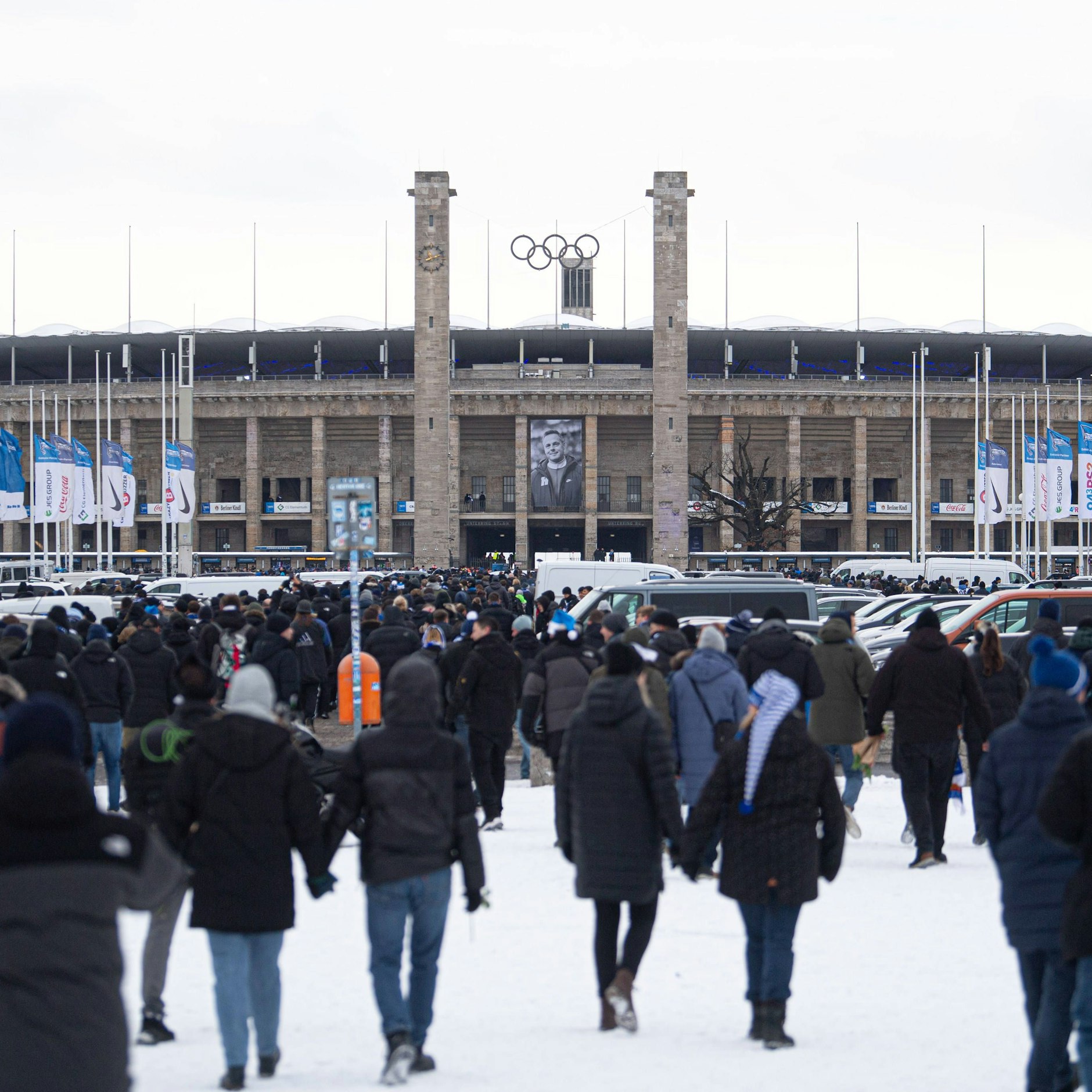 Fans auf dem schweren Weg zum Olympiastadion. Ein Riesenporträt von Kay Bernstein hängt an der Arena.