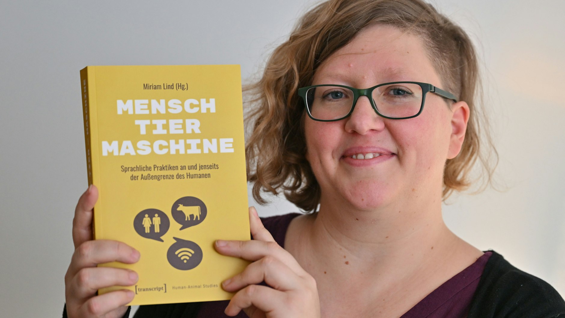 Miriam Lind, die Leiterin der Gruppe Posthumanistische Linguistik. Kommunikative Praktiken zwischen Menschen, Tieren und Maschinen an der Europa-Universität Viadrina, zeigt ihr Buch „Mensch, Tier, Maschine“.