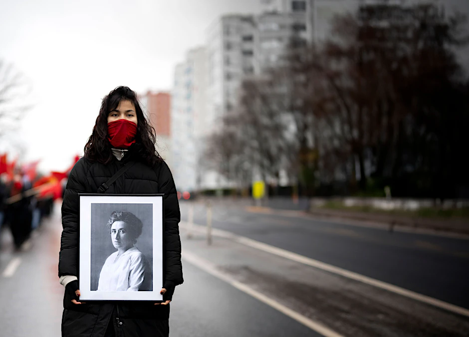 Eine Demonstrantin trägt am Luxemburg-Liebknecht-Gedenktag ein Foto von Rosa Luxemburg.