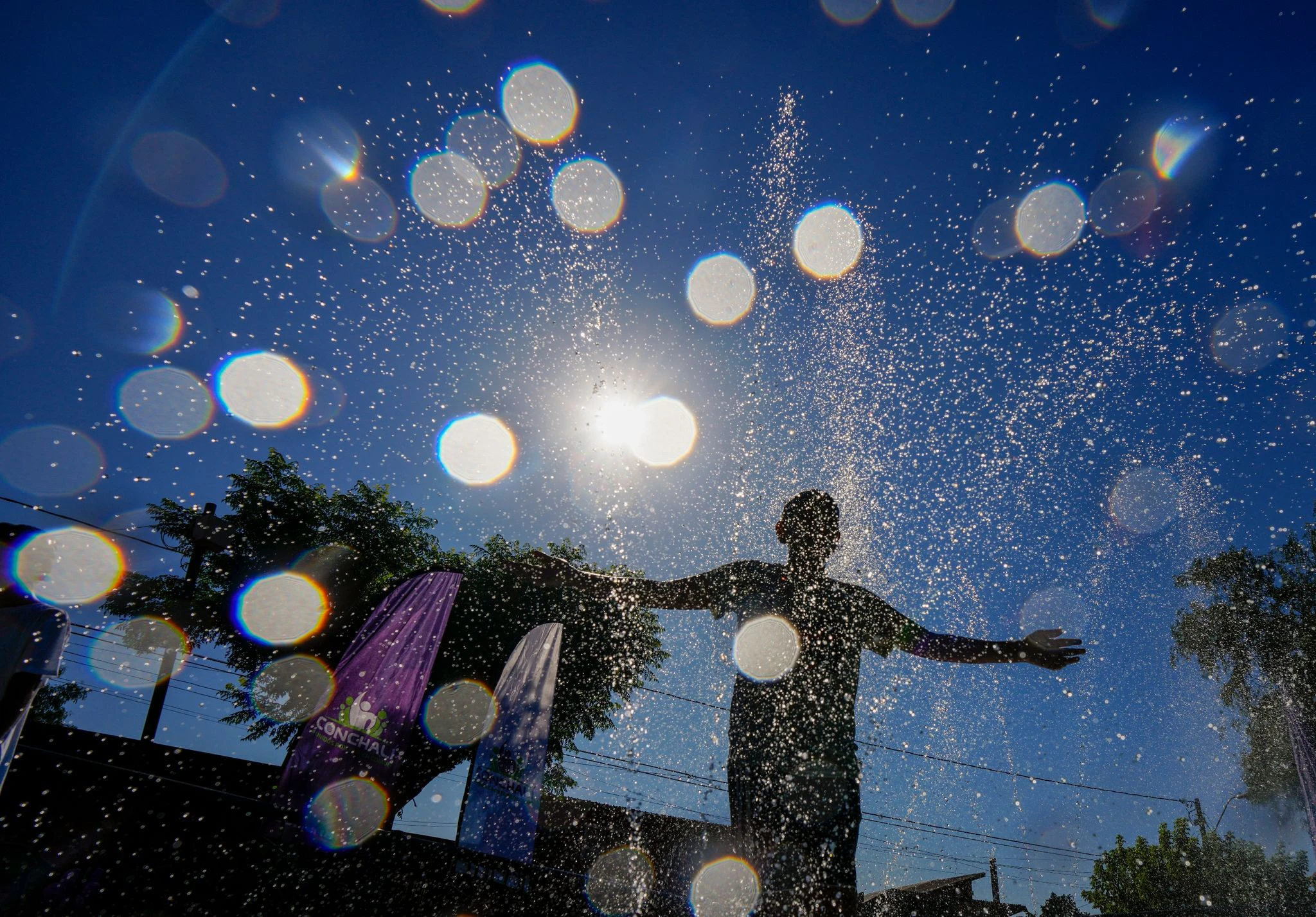 Während es in Deutschland regnet oder eisig kalt ist, genießt dieser Junge im chilenischen Santiago einen angenehmen Sommertag. Da ist jede Abkühlung willkommen!  