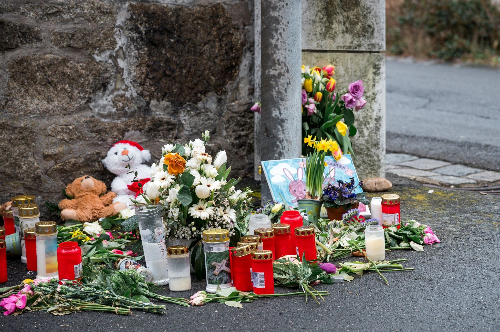 ARCHIV - An einer Mauer vor dem Kinder- und Jugendheim in Wunsiedel, in dem eine Zehnjährige tot aufgefunden wurde, liegen Blumen, Kerzen und Stofftiere.  