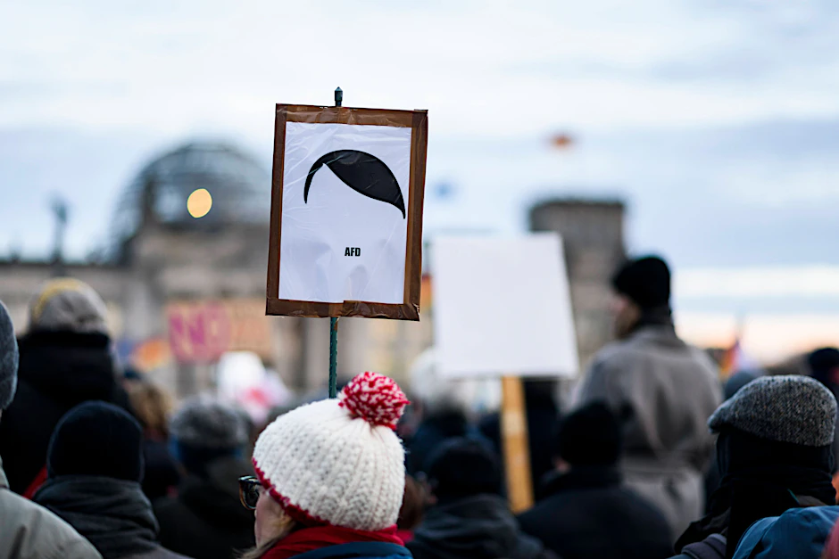 Auf einer Kundgebung gegen Rechtsextremismus verpasst eine Demonstrantin der AfD einen auffälligen Seitenscheitel.
