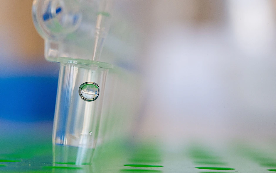 ARCHIV - Eine Wissenschaftlerin füllt eine Flüssigkeit mit einer Pipette in einen Behälter.  