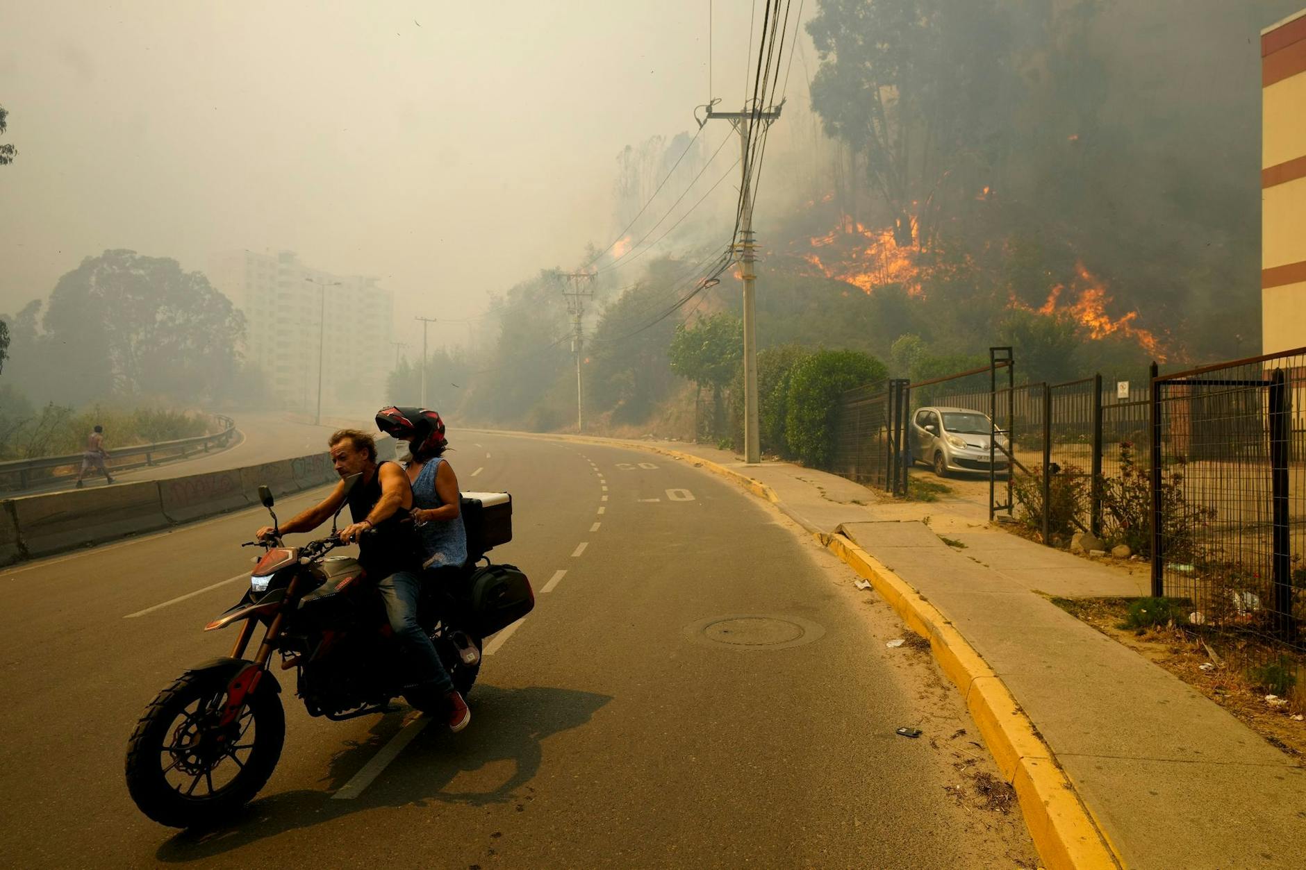 Anwohner in Chile bringen sich auf einem Motorrad in Sicherheit, während der Rauch der Waldbrände den Himmel füllt.