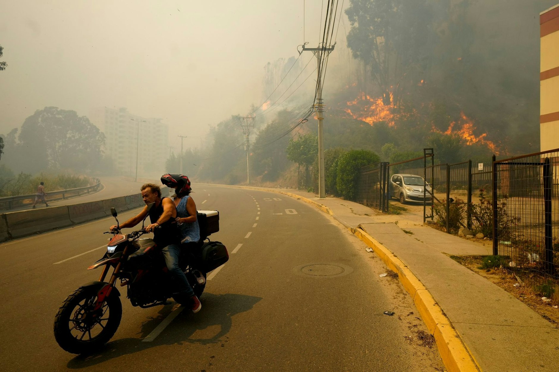 Anwohner in Chile bringen sich auf einem Motorrad in Sicherheit, während der Rauch der Waldbrände den Himmel füllt.  