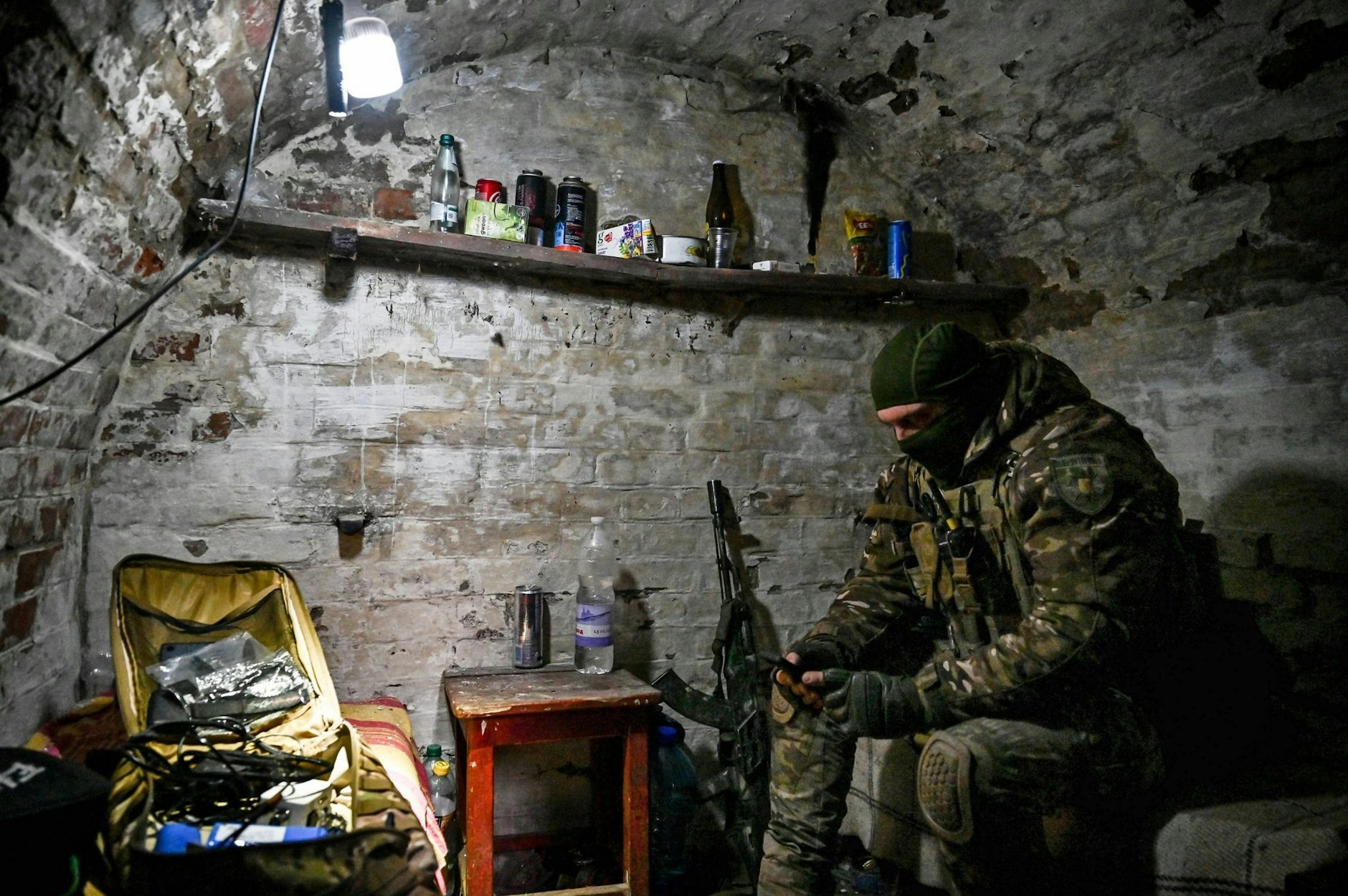 dpatopbilder - Kontakt nach draußen: Ein Mitglied einer ukrainischen Polizeieinheit sitzt in einem Keller bei Orichiw und blickt auf sein Smartphone.  nform.com/ Ukrinform/dpa