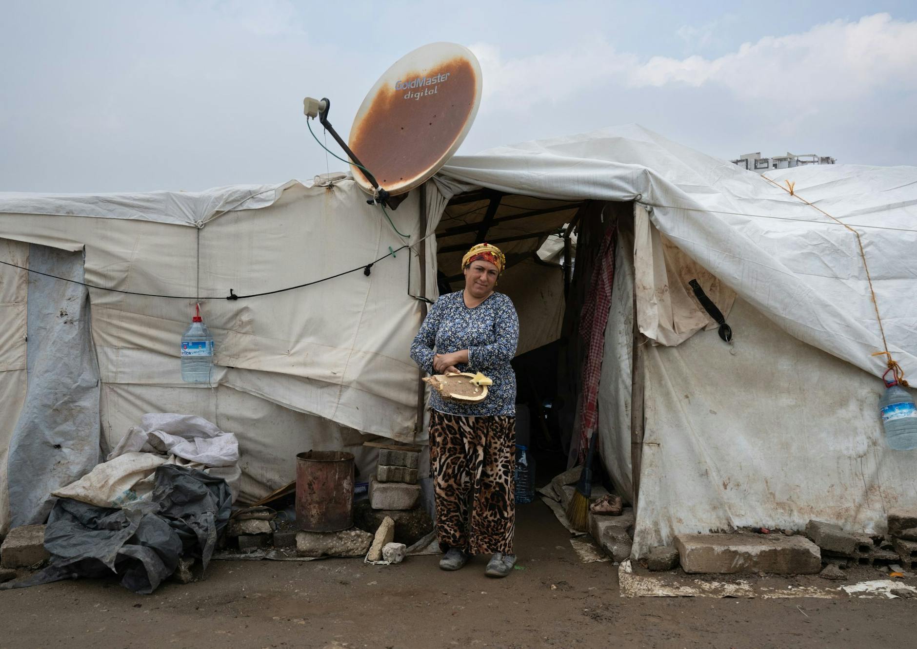 dpatopbilder - Eine Frau steht vor ihrem Zelt, in dem sie nach dem Erdbeben untergekommen ist. Vor knapp einem Jahr töteten die Beben in der Türkei mehr als 53.000 Menschen. Hunderttausende Menschen leben weiterhin in Containern und Zelten.