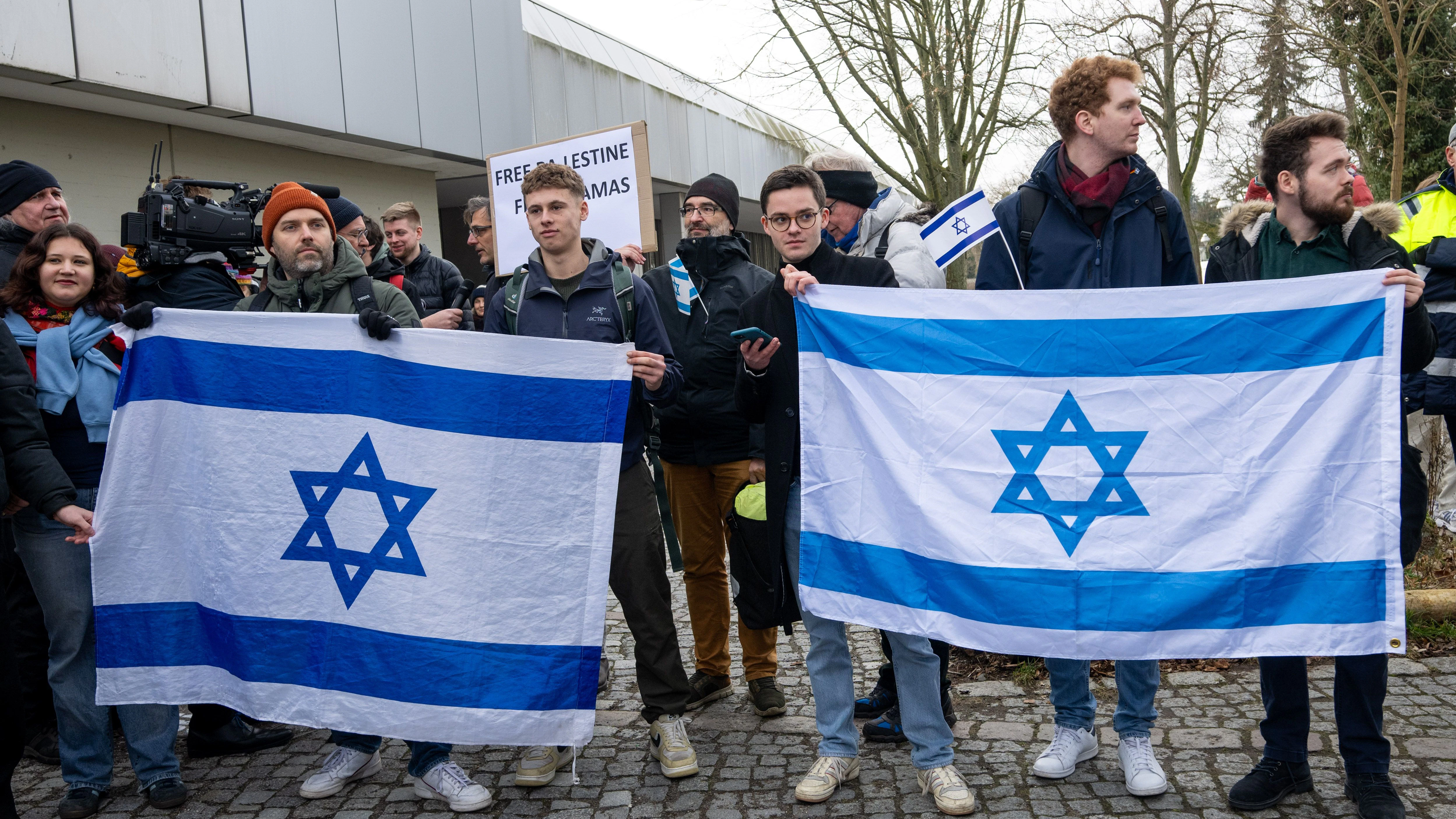 Teilnehmer einer Gegenkundgebung halten israelische Fahnen am Rande einer propalästinensischen Kundgebung. 