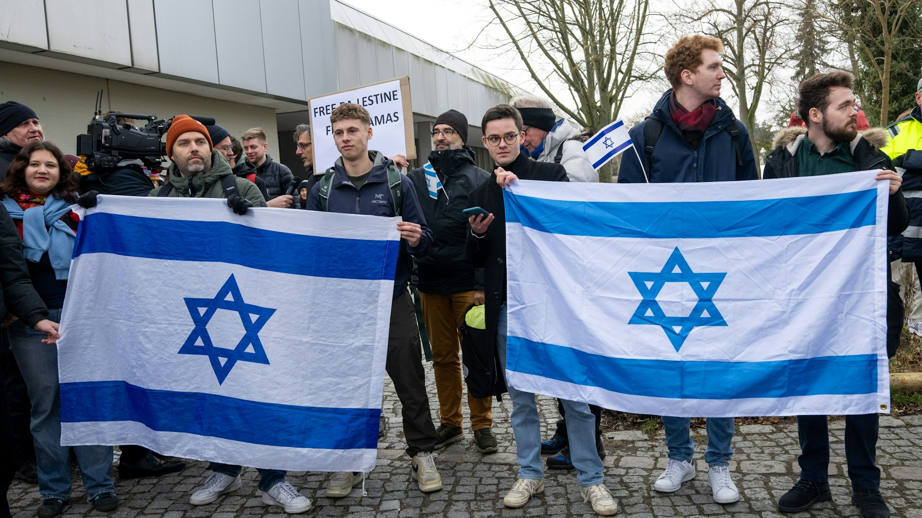 Teilnehmer einer Gegenkundgebung halten israelische Fahnen am Rande einer propalästinensischen Kundgebung. 