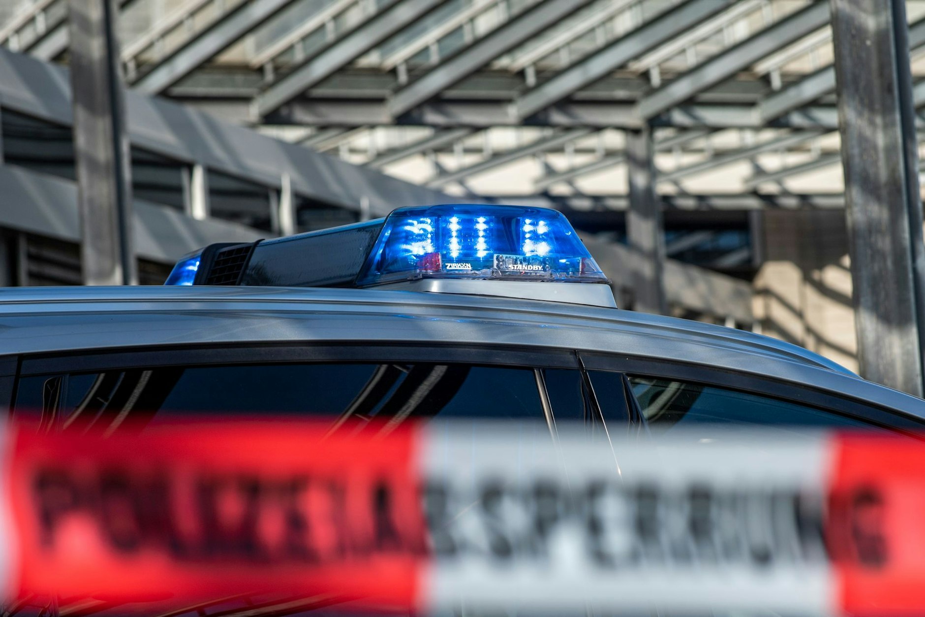 Ein Polizei-Blaulicht leuchtet über einem Absperrband mit der Aufschrift „Polizeiabsperrung“.