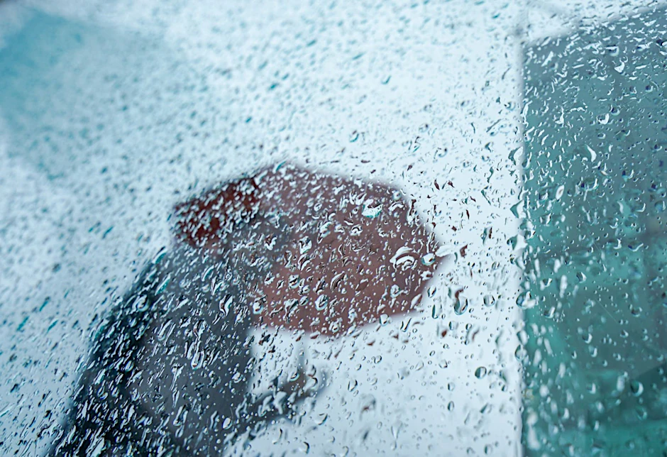 Ein Passant mit Regenschirm.  