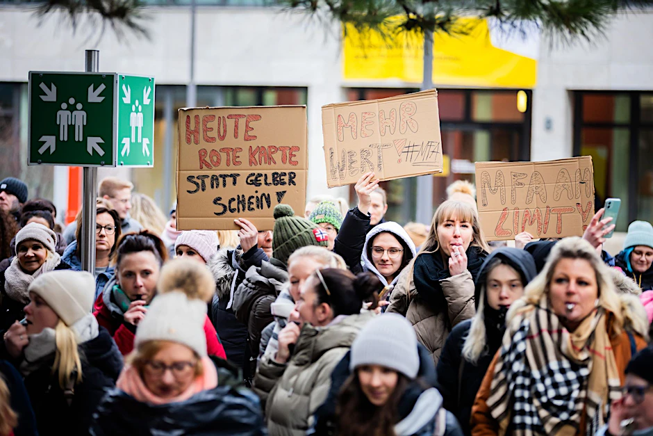 Medizinische Fachangestellte halten bei einer Kundgebung in Berlin Schilder vor der Bundesärztekammer in die Höhe.  