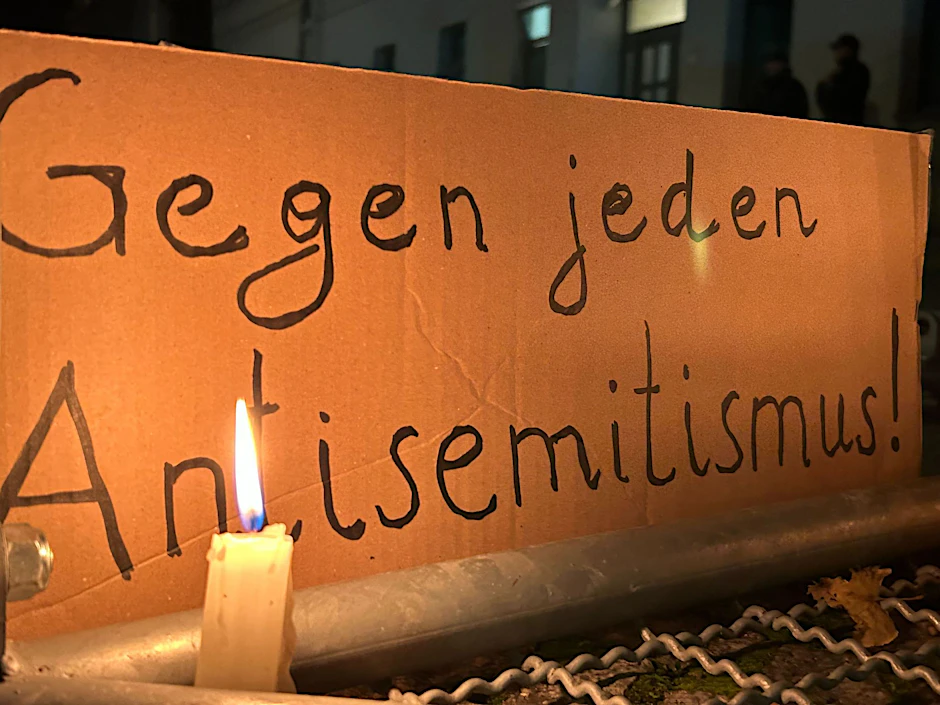 ARCHIV - Eine brennende Kerze steht vor einem Schild mit der Aufschrift «Gegen jeden Antisemitismus».  