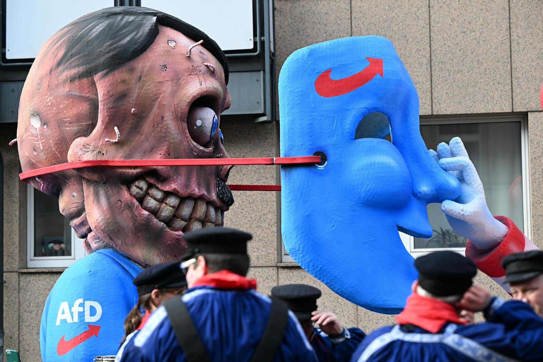 Auf einem Mottowagen beim Rosenmontagsumzug in Düsseldorf wird enthüllt, was hinter der AfD-Maske steckt: der Totenschädel von Adolf Hitler.