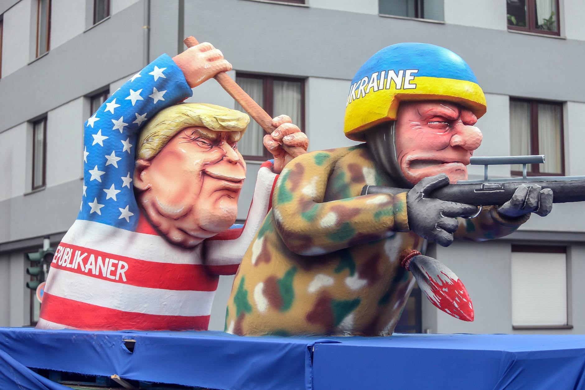 Ebenfalls in Düsseldorf sticht der wahrscheinliche US-Präsidentschaftskandidat der Republikaner und Ex-Präsident Donald Trump einem kämpfenden ukrainischen Soldaten mit einer Lanze in den Rücken.