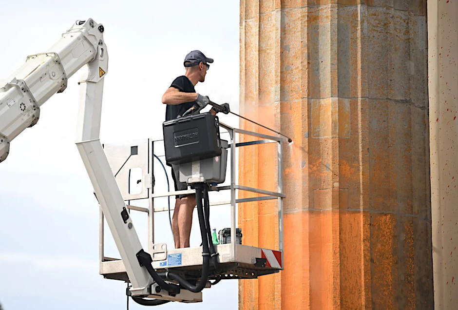 ARCHIV - Ein Arbeiter entfernt die Farbrückstände am Brandenburger Tor.  
