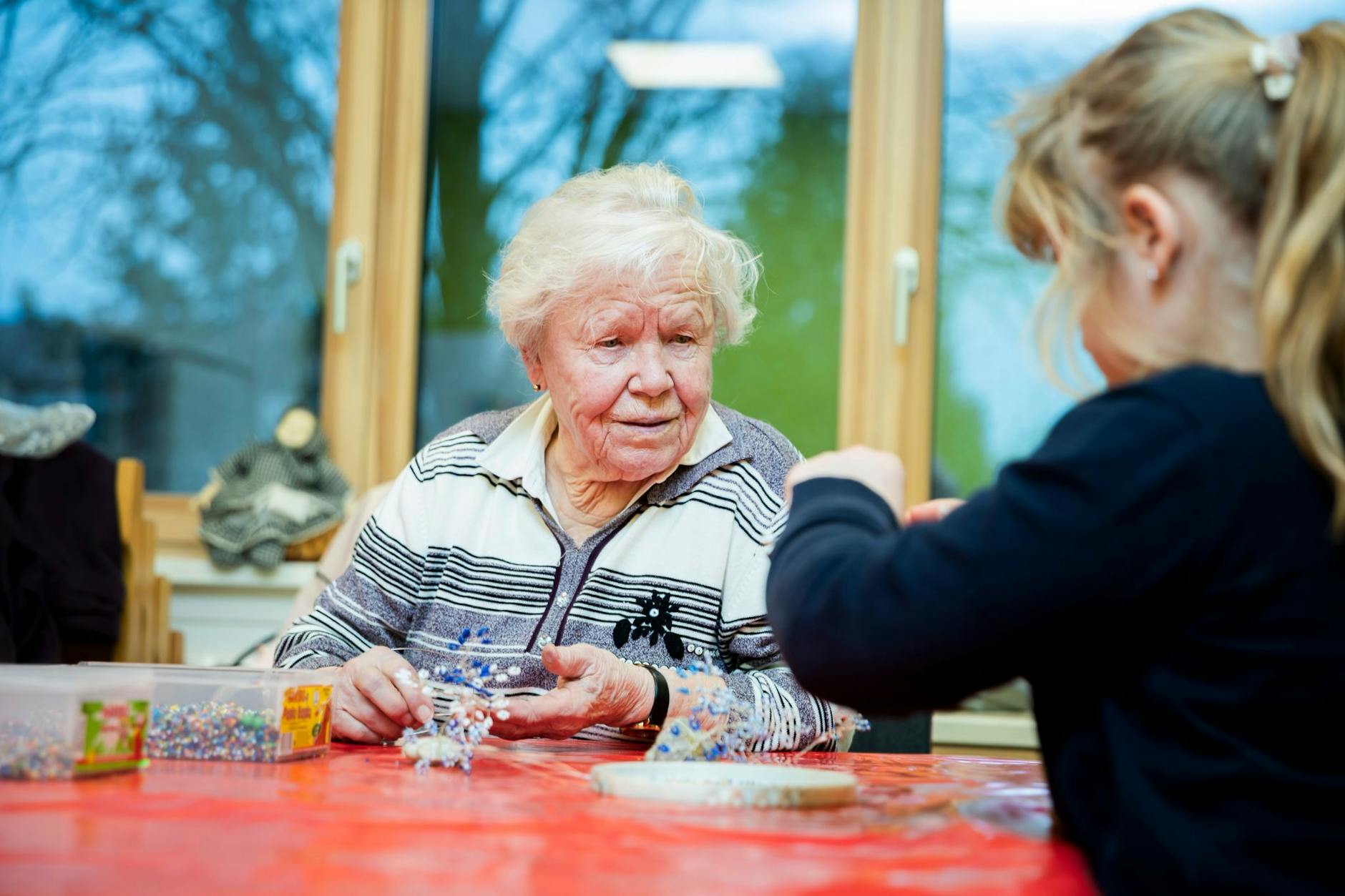 Kinderclub-Mitarbeiterin Vera May bastelt im Kinderclubhaus in Berlin-Neukölln mit einem Mädchen ein Perlenbäumchen. 