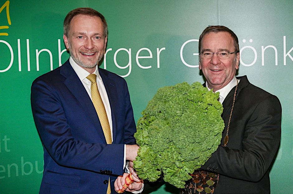 Christian Lindner (l) übergibt dem neuen Oldenburger Grünkohlkönig Boris Pistorius mit einer Grünkohlpflanze sein Ehrenamt.  