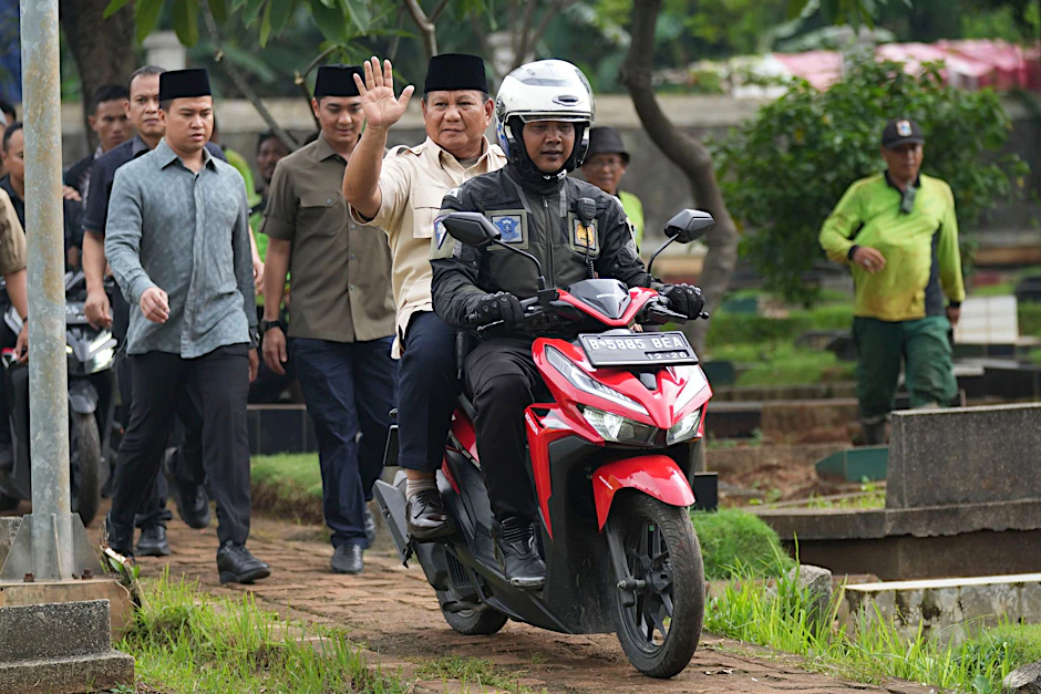 Prabowo Subianto wird von einem Polizisten zum Grab seines Vaters in Jakarta gefahren.  