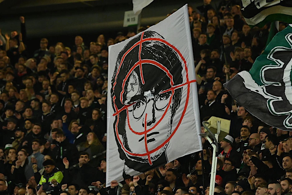 Hannover-Fans halten ein Fadenkreuz-Plakat mit dem Gesicht des Film-Zauberers Harry Potter hoch.  