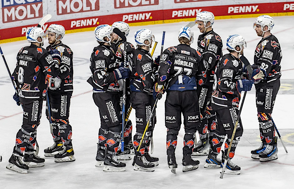 Spieler der Eisbären Berlin klatschen sich nach dem Sieg ab.  