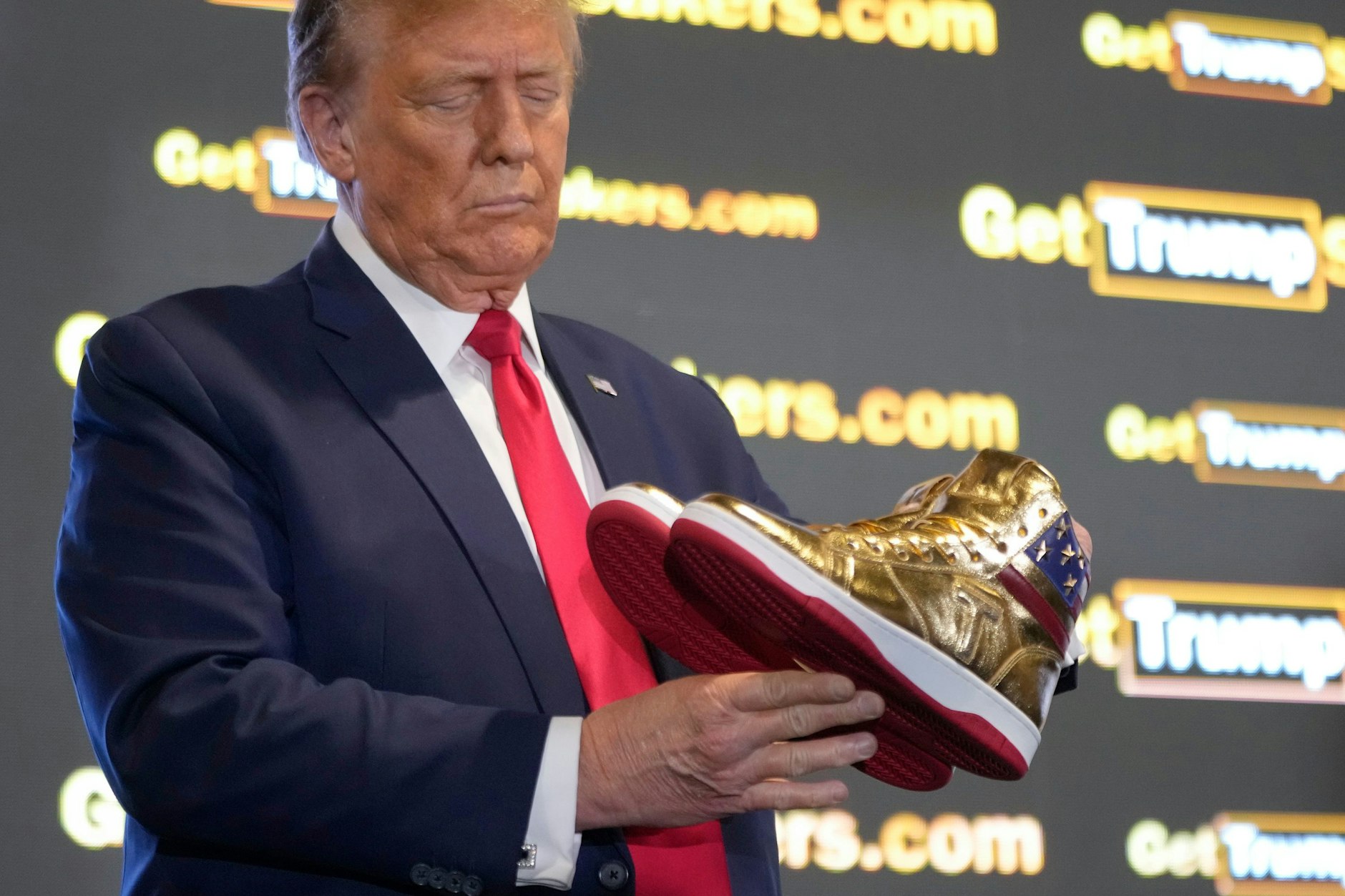 Der republikanische Präsidentschaftskandidat und Ex-Präsident Donald Trump hält goldene Trump-Sneakers in Händen.