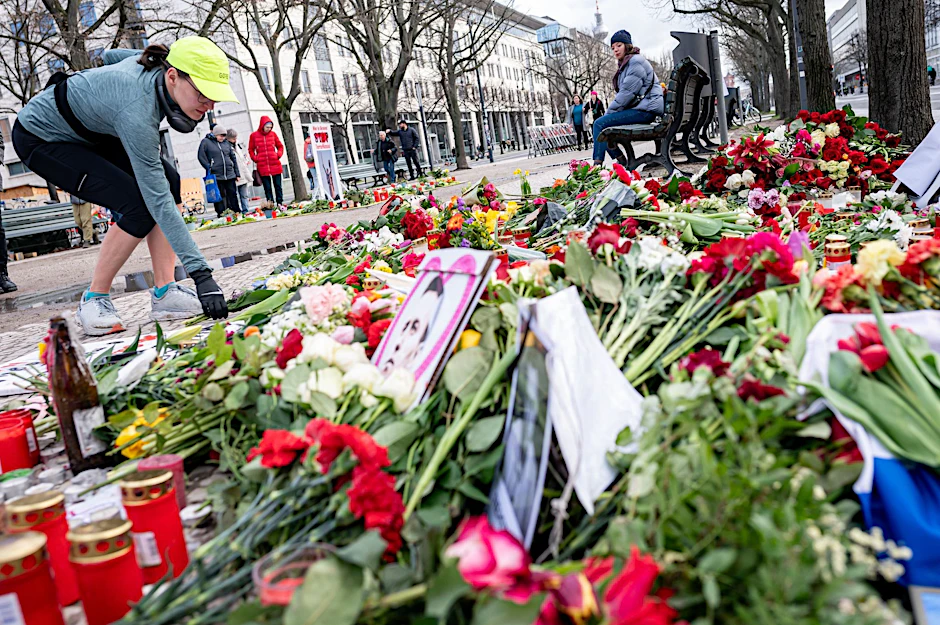 Eine Frau legt nach dem Tod Nawalnys vor der russischen Botschaft Blumen nieder.  