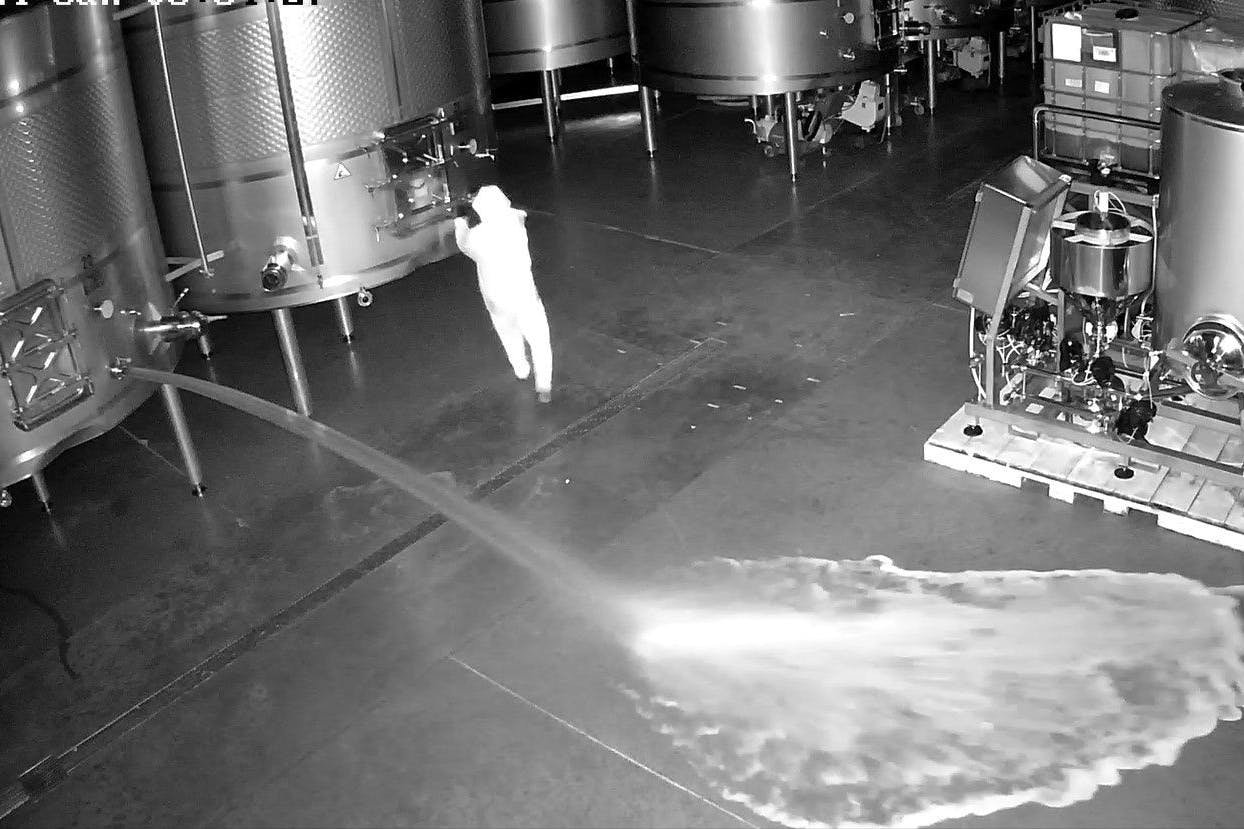 Auf dieser Aufnahme einer Sicherheitskamera ist eine Person zu sehen, die im Lagerraum des Weinguts Cepa 21 die Hähne von Weintanks öffnet.