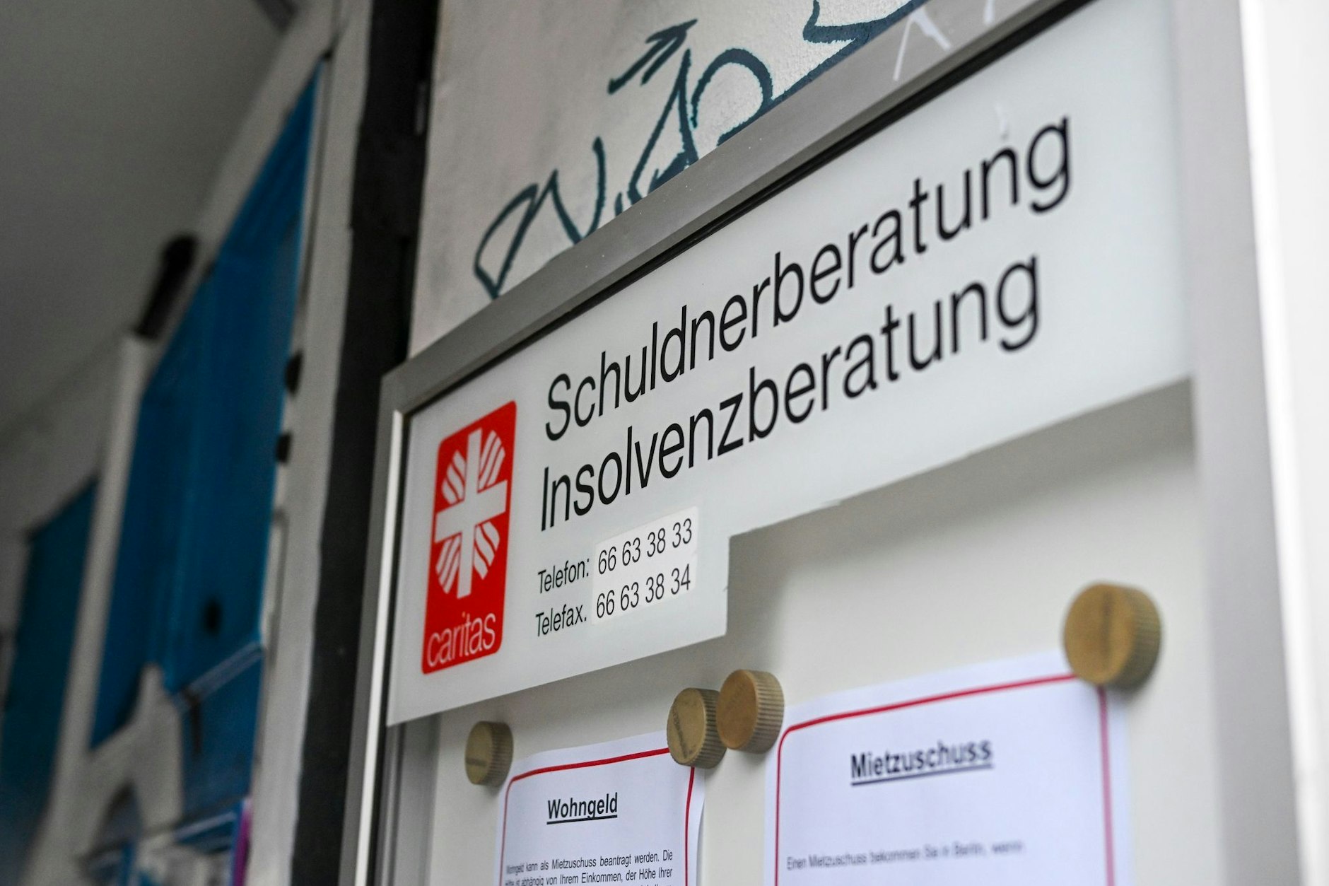 Eine Schuldnerberatung und Insolvenzberatung der Caritas ist an einem Eingang in der Schönhauser Allee in Pankow ausgeschildert.