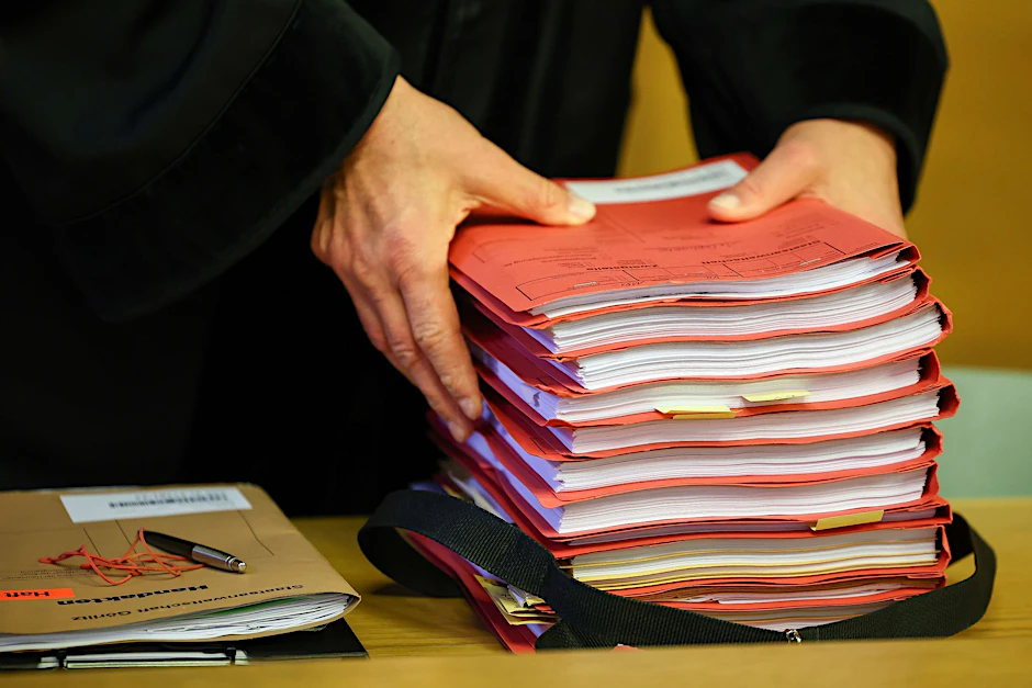 ARCHIV - Ein Staatsanwalt legt einen Stapel Akten vor Prozessbeginn auf seinen Tisch im Gericht.  