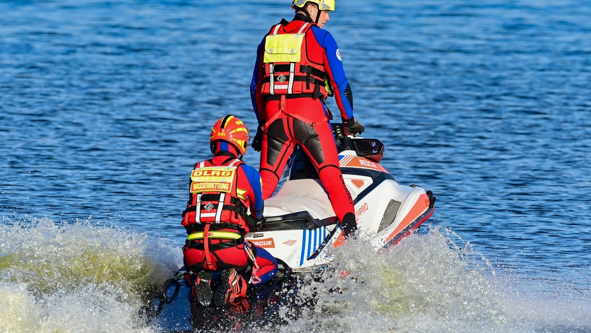 Zwei DLRG-Einsatzkräfte sind mit einem Jetski bei einer Wasserrettungsübung zu sehen.