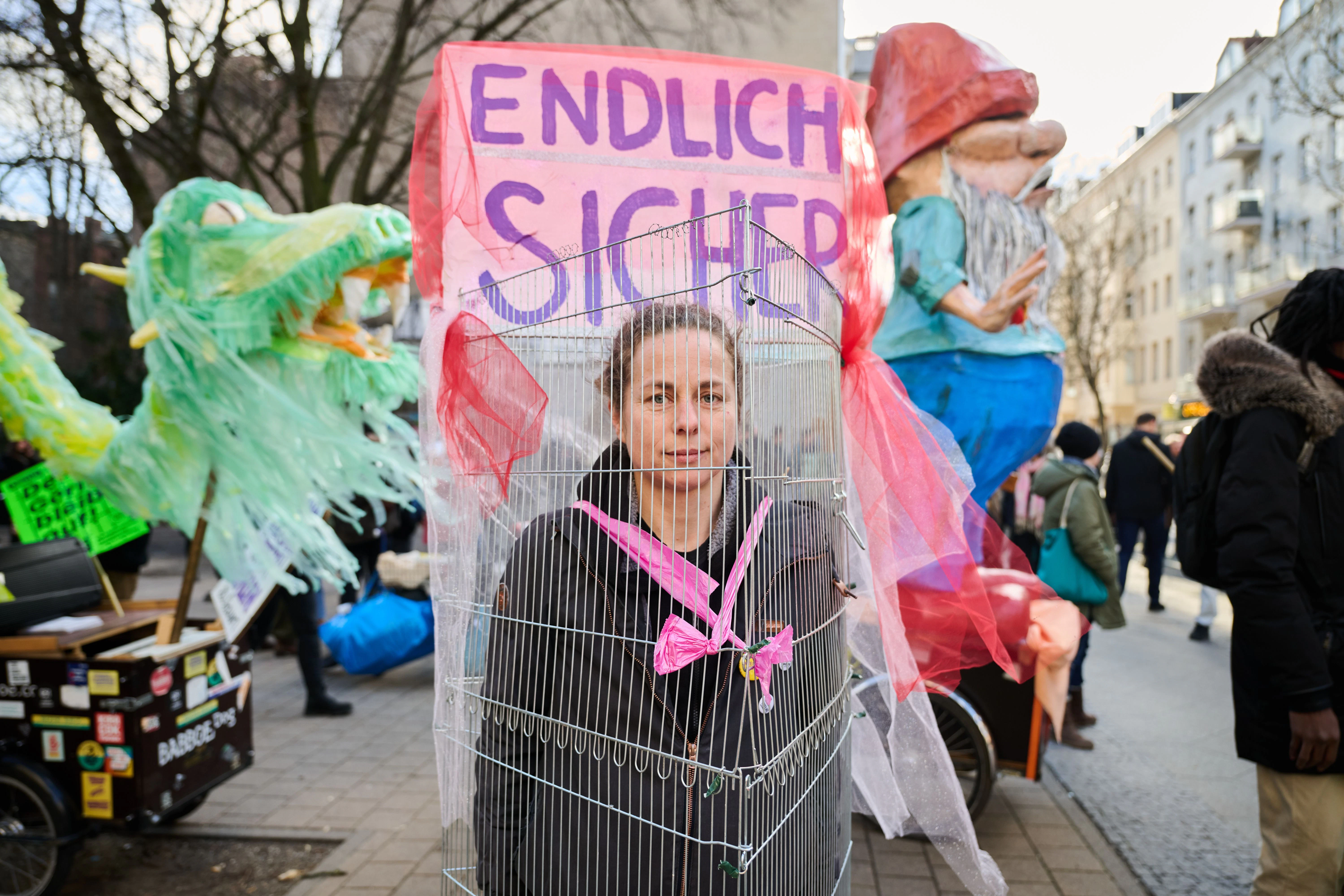 Eine Demonstrantin hat sich symbolisch in einen Käfig gesperrt. „Endlich sicher“ steht auf ihrem Plakat.