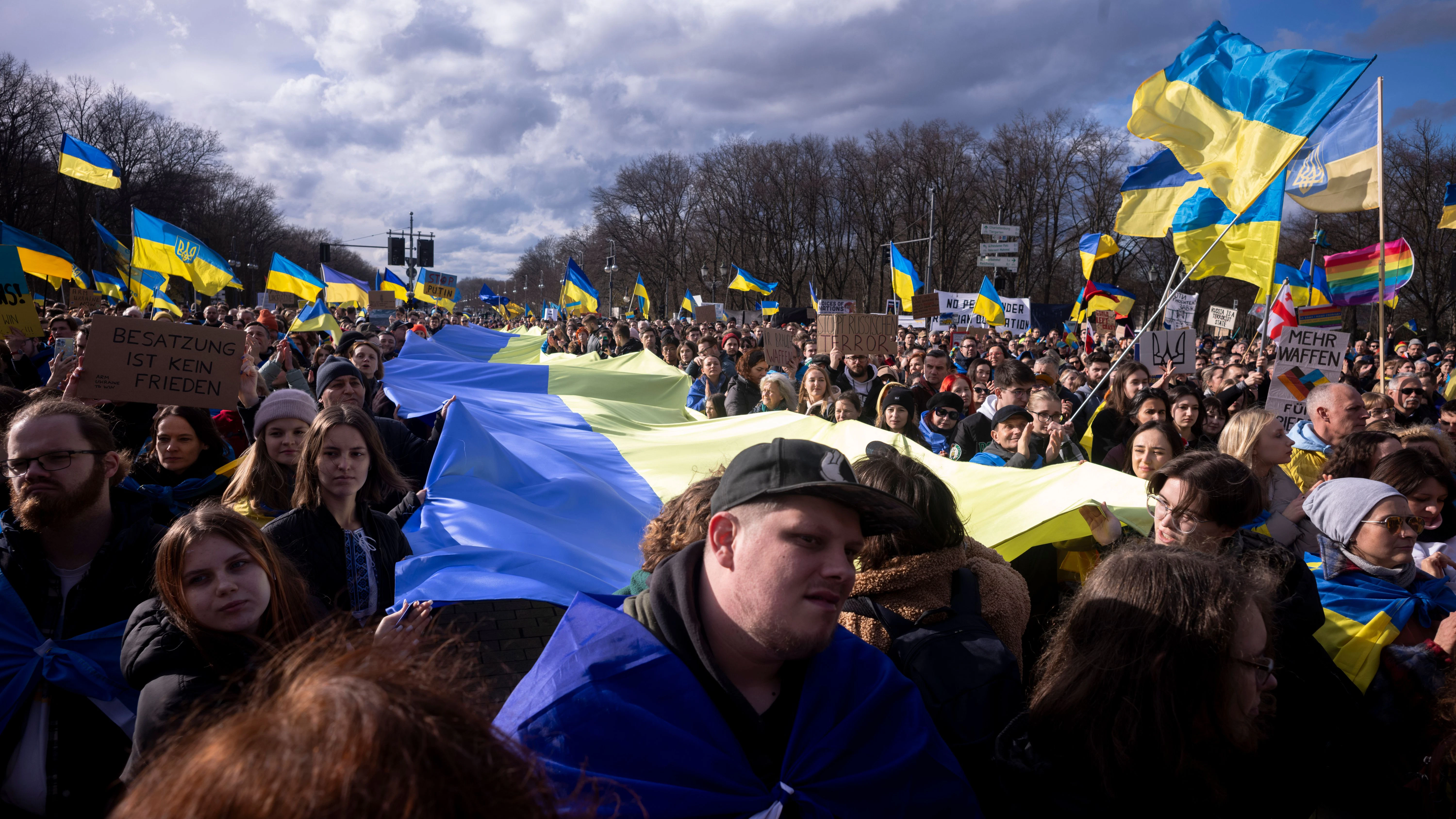 Teilnehmer der Ukraine-Demo in Berlin halten eine riesige ukrainische Flagge.