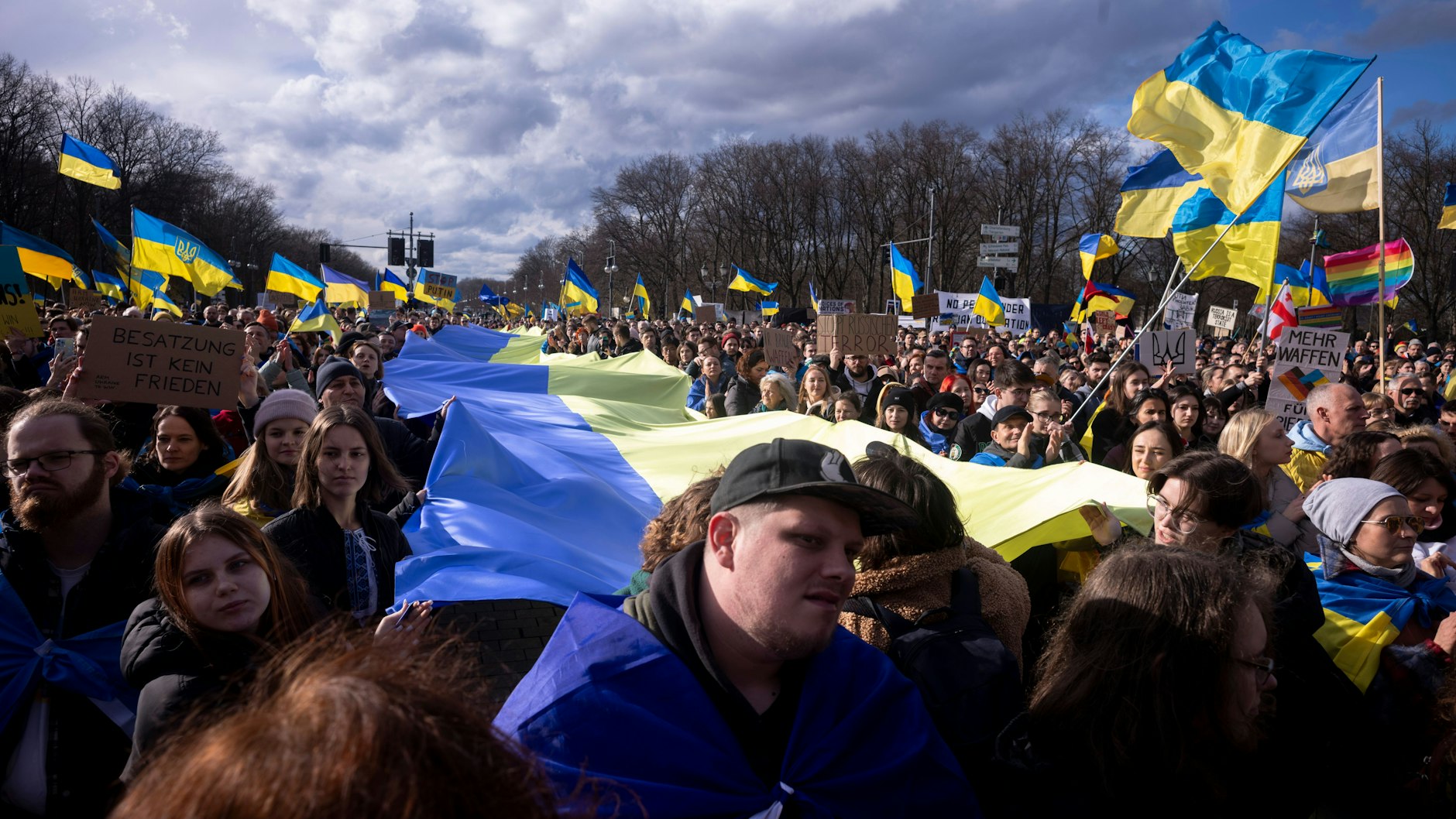 Teilnehmer der Ukraine-Demo in Berlin halten eine riesige ukrainische Flagge.
