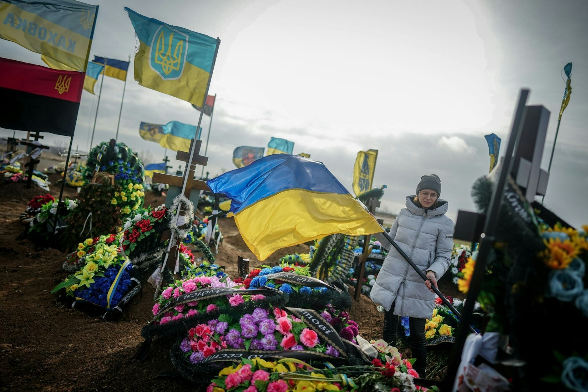 Eine Angehörige steht auf einem Friedhof in der ukrainischen Hafenstadt Odessa. Die Gräber gefallener ukrainischer Soldaten sind an den Fahnen zu erkennen. 