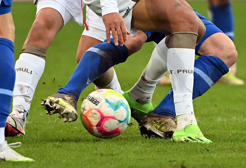 Fußballspieler zweier gegnerischer Mannschaften kämpfen um den Ball.  