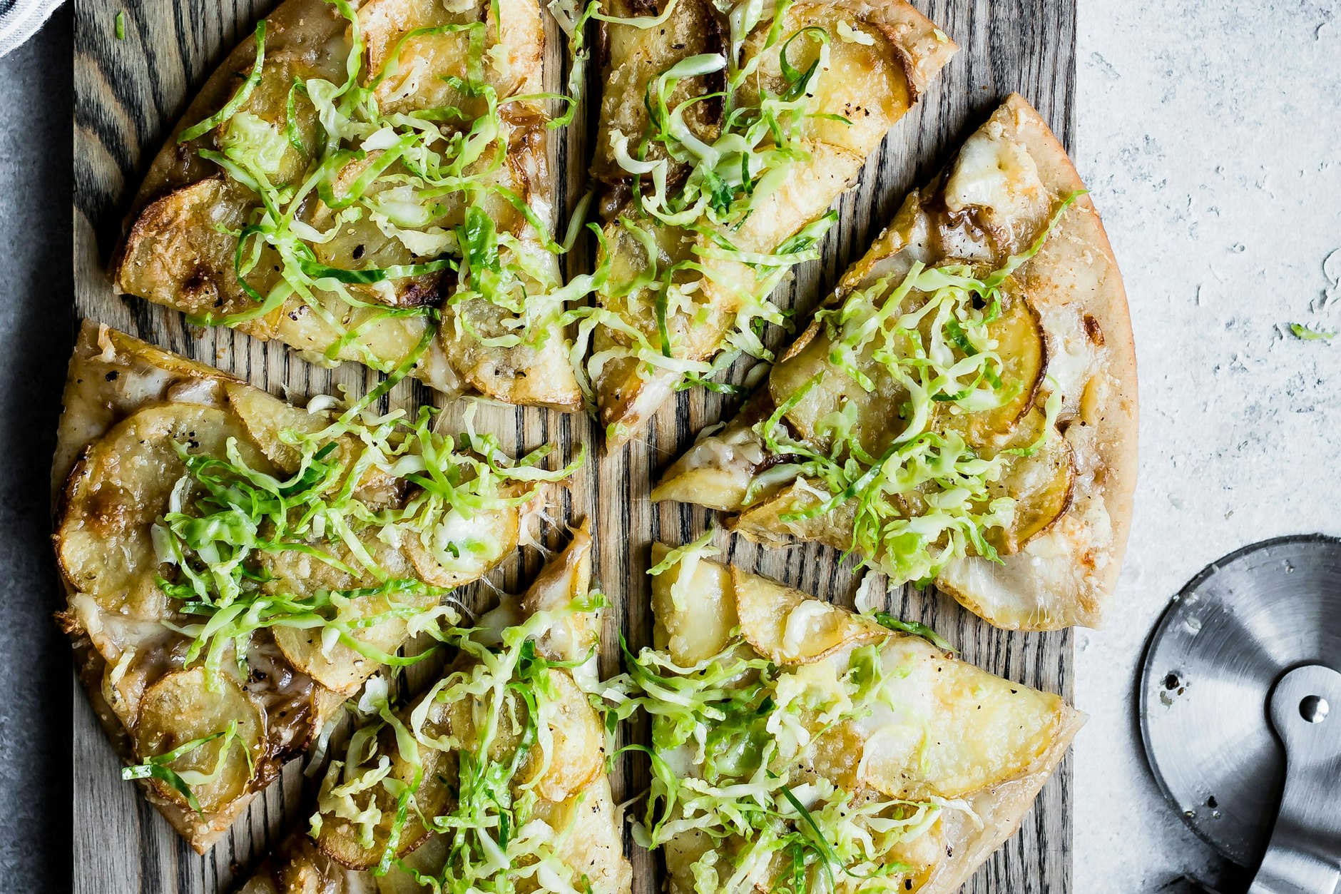 Frisch gebackene Rosenkohl-Pizza mit geschmolzenem Käse, knusprigem Speck, serviert auf einem rustikalen Holzbrett.