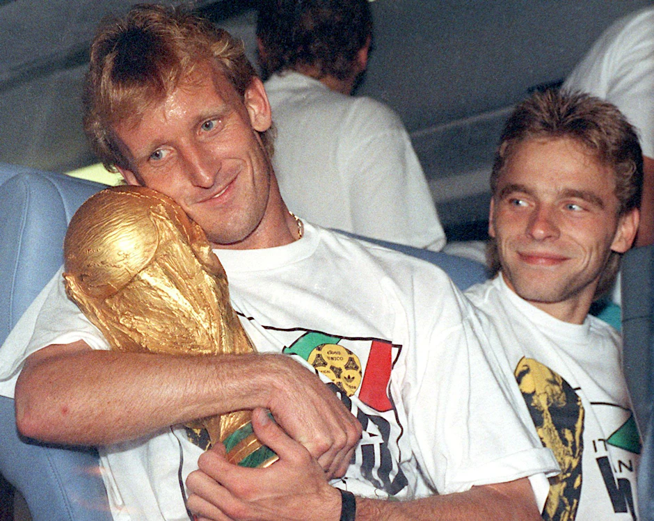 ARCHIV - Andreas Brehme (l) mit dem WM-Pokal nach dem Finalsieg 1990 gegen Argentinien. Rechts daneben sein Mitspieler Thomas Häßler.  