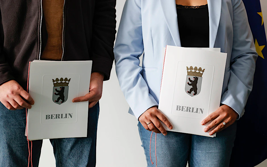 Eingebürgerte in Berlin zeigen ihre Einbürgerungsurkunde. Fast jeder vierte Berliner hatte 2023 keinen deutschen Pass.