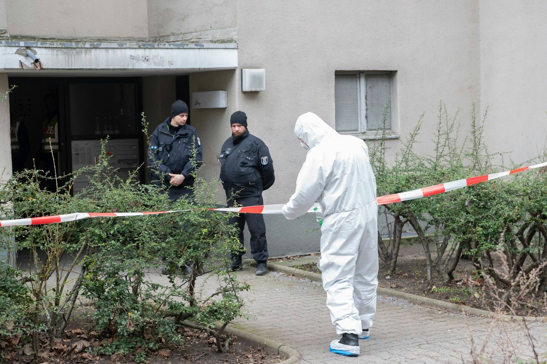 Polizisten stehen am Eingang eines Mehrfamilienhauses in Stadtteil Kreuzberg.