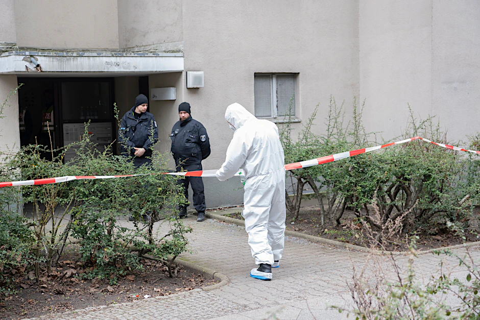 Polizisten stehen am Eingang eines Mehrfamilienhauses in Stadtteil Kreuzberg.