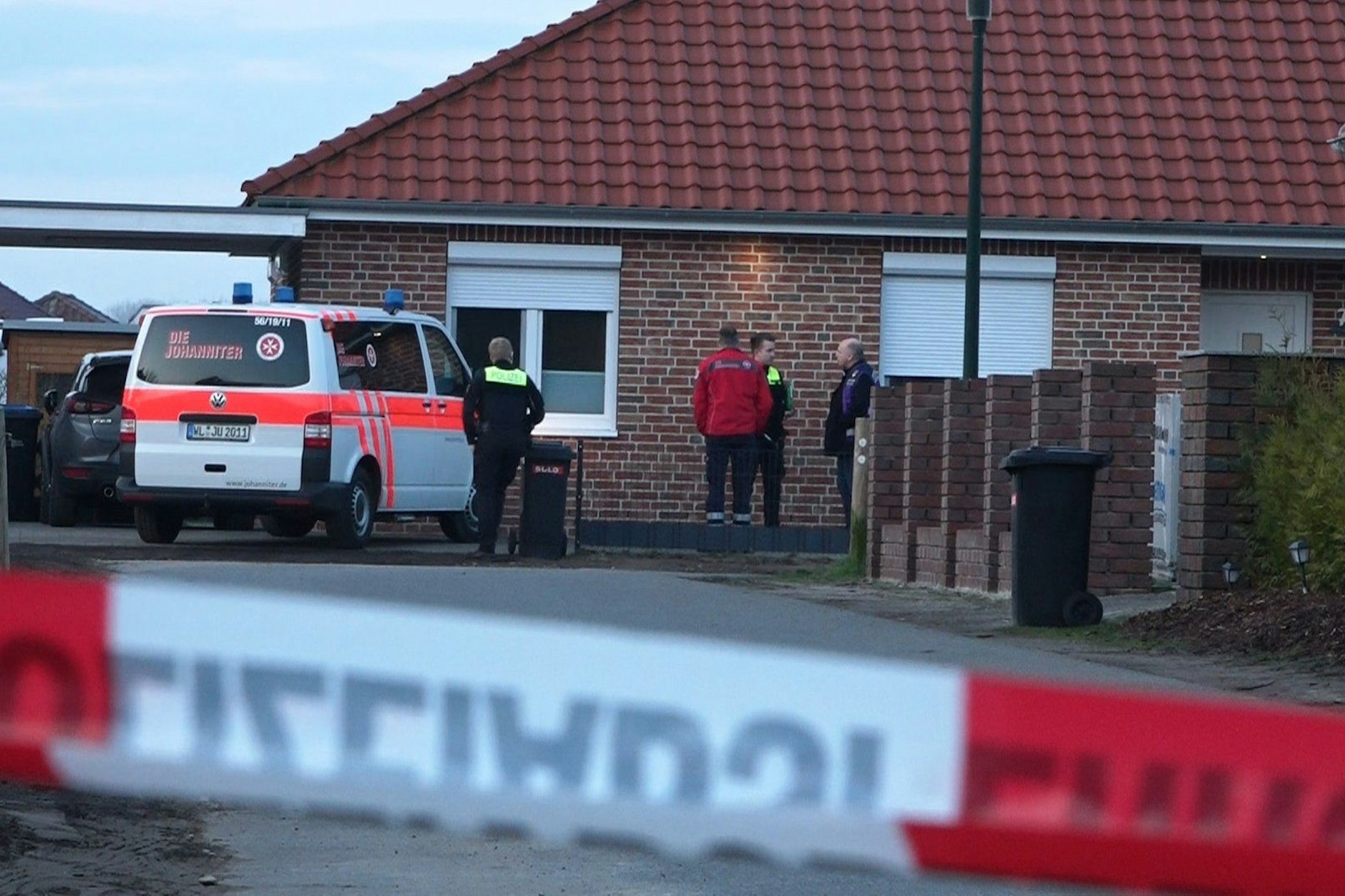 Einsatzkräfte stehen hinter einem Absperrband. Die Polizei ermittelt nach Schüssen im Landkreis Rotenburg wegen möglicher Kapitaldelikte.