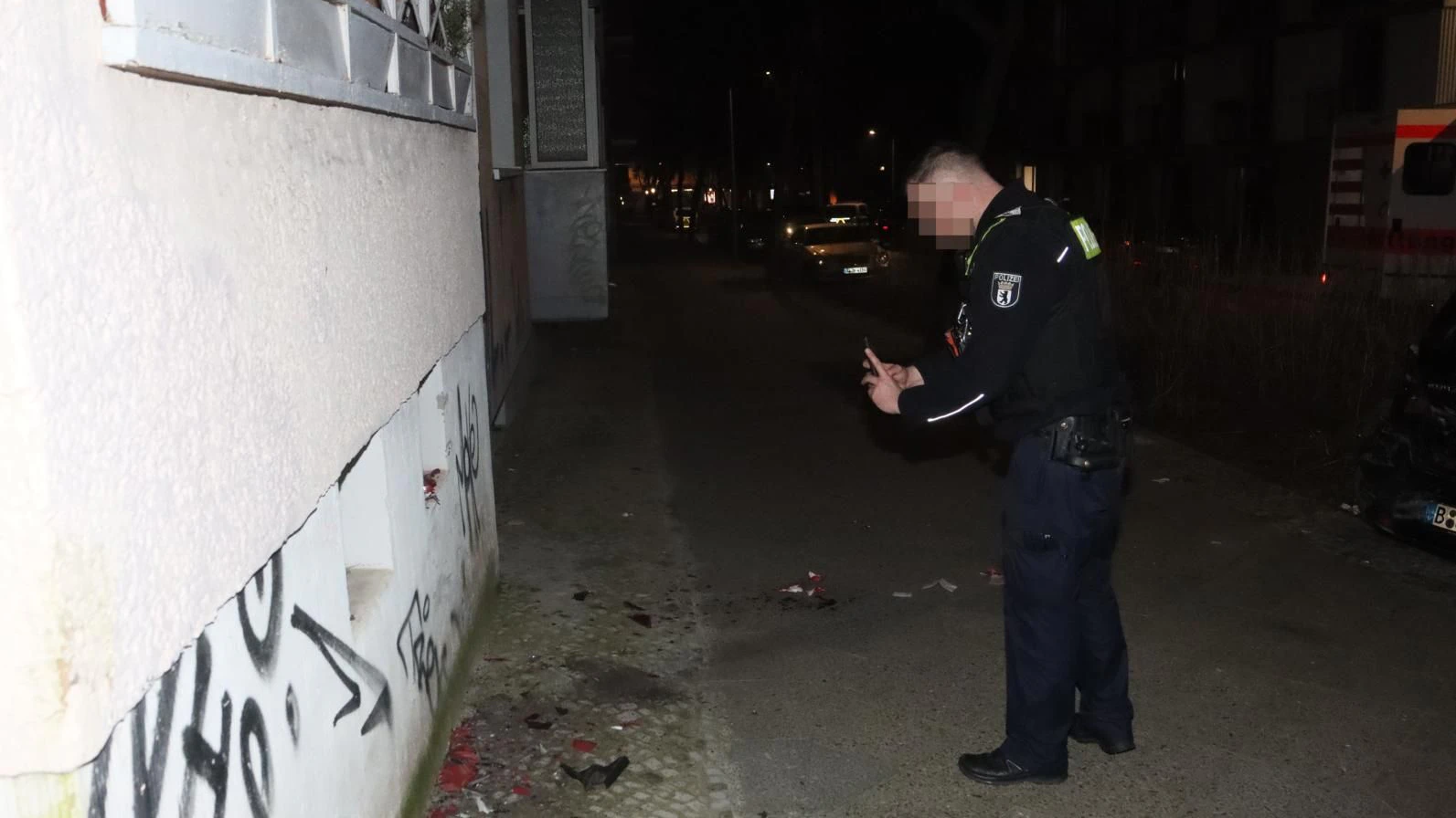Ein Beamter der Polizei dokumentiert die Unfallstelle. Auf dem Gehweg liegen noch die Splitter der Rückleuchter des Wagens, der hier in eine Hauswand krachte.
