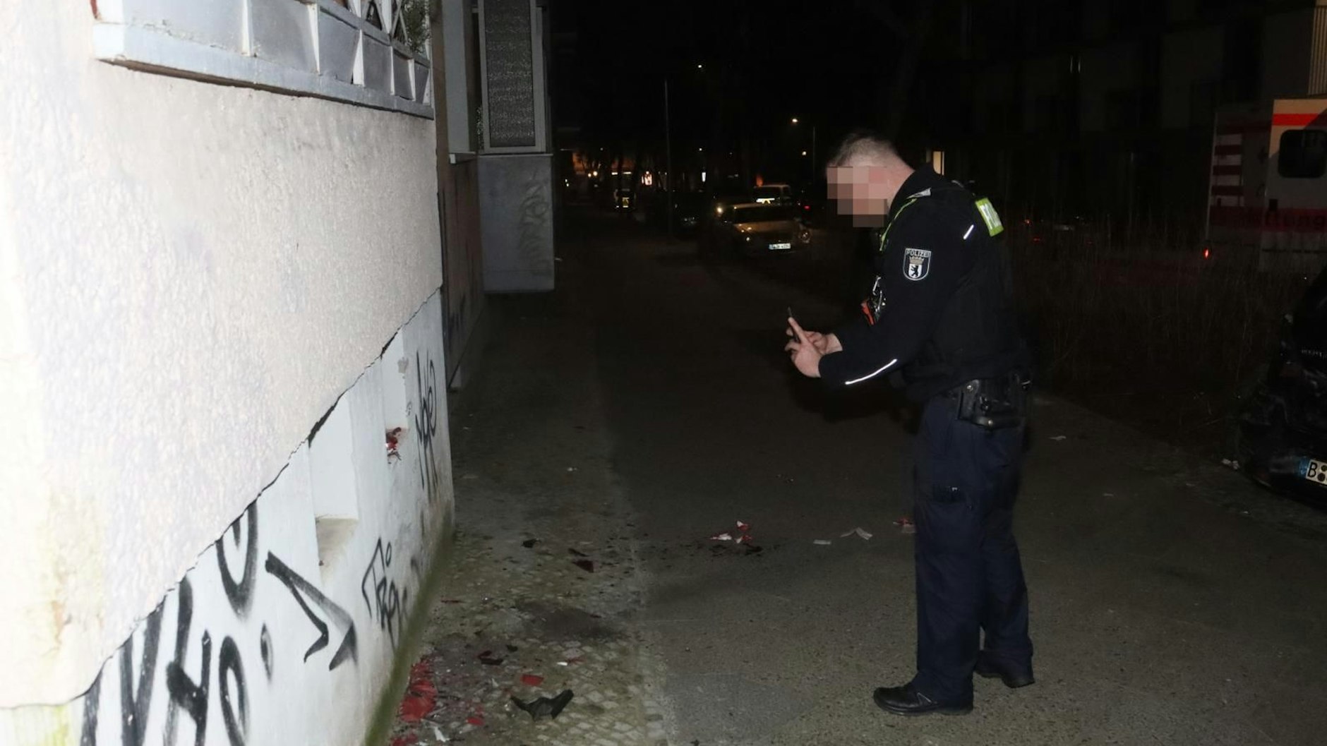 Ein Beamter der Polizei dokumentiert die Unfallstelle. Auf dem Gehweg liegen noch die Splitter der Rückleuchter des Wagens, der hier in eine Hauswand krachte.