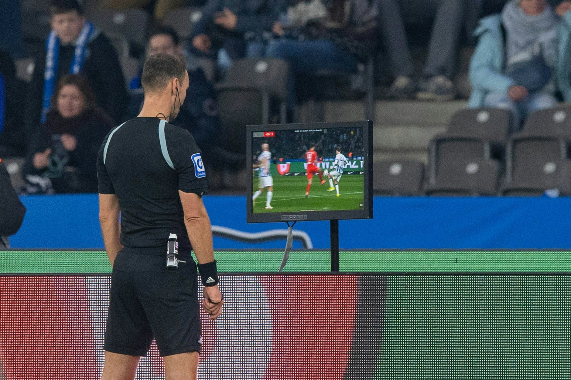 Schiri Bastian Dankert überprüft die Szene des angeblichen Fouls durch Herthas Linus Gechter und entscheidet in der Nachspielzeit auf Elfmeter für Holstein Kiel.