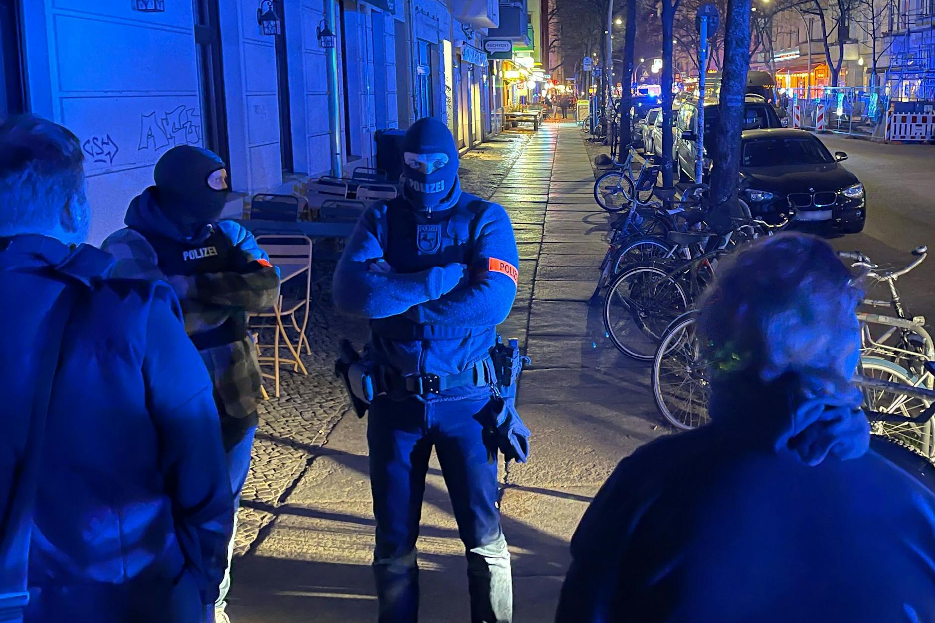Polizisten mit Sturmmasken stehen vor einem Wohnhaus an der Grünberger Straße. 