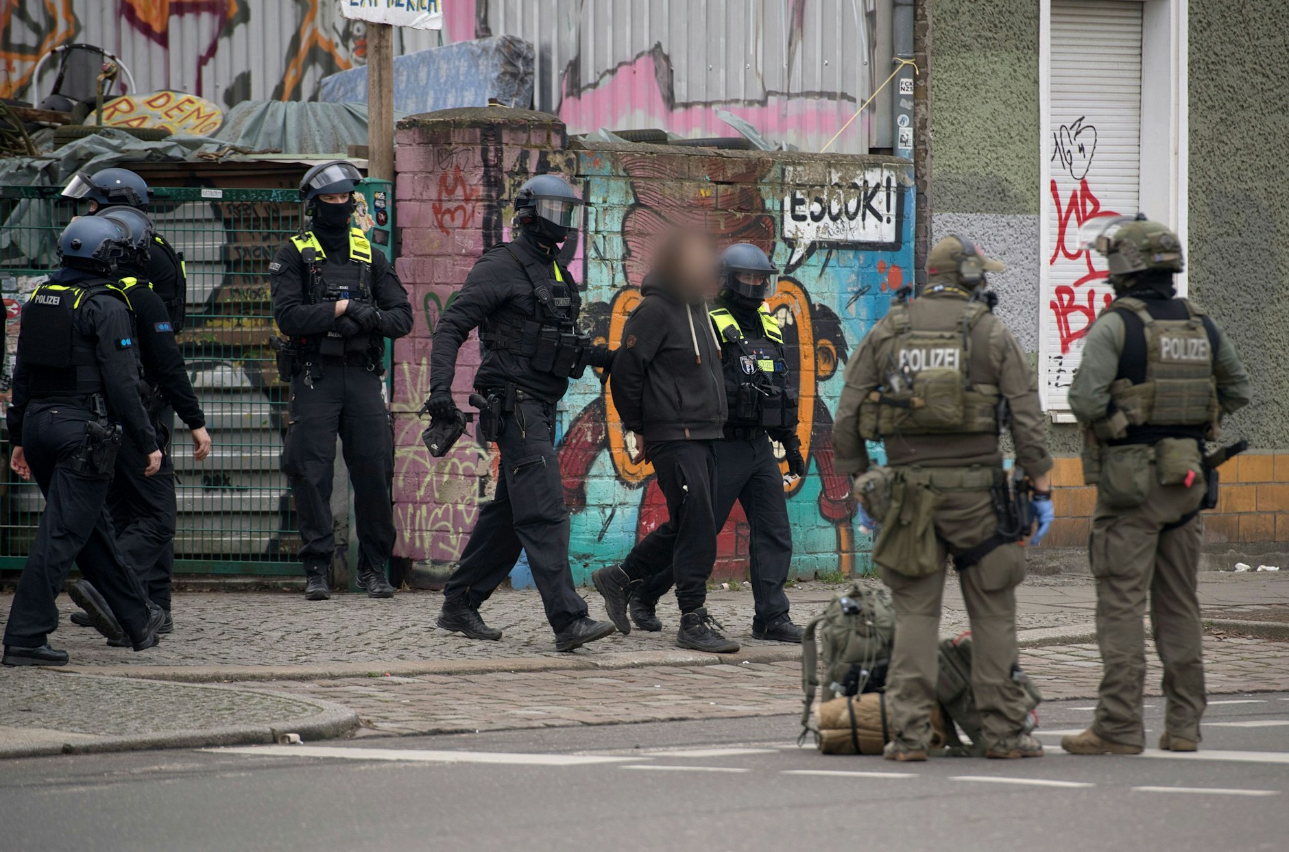 Polizisten nehmen am Sonntagmorgen einen Mann fest und führen ihn ab. Wer er ist, ist noch unklar.