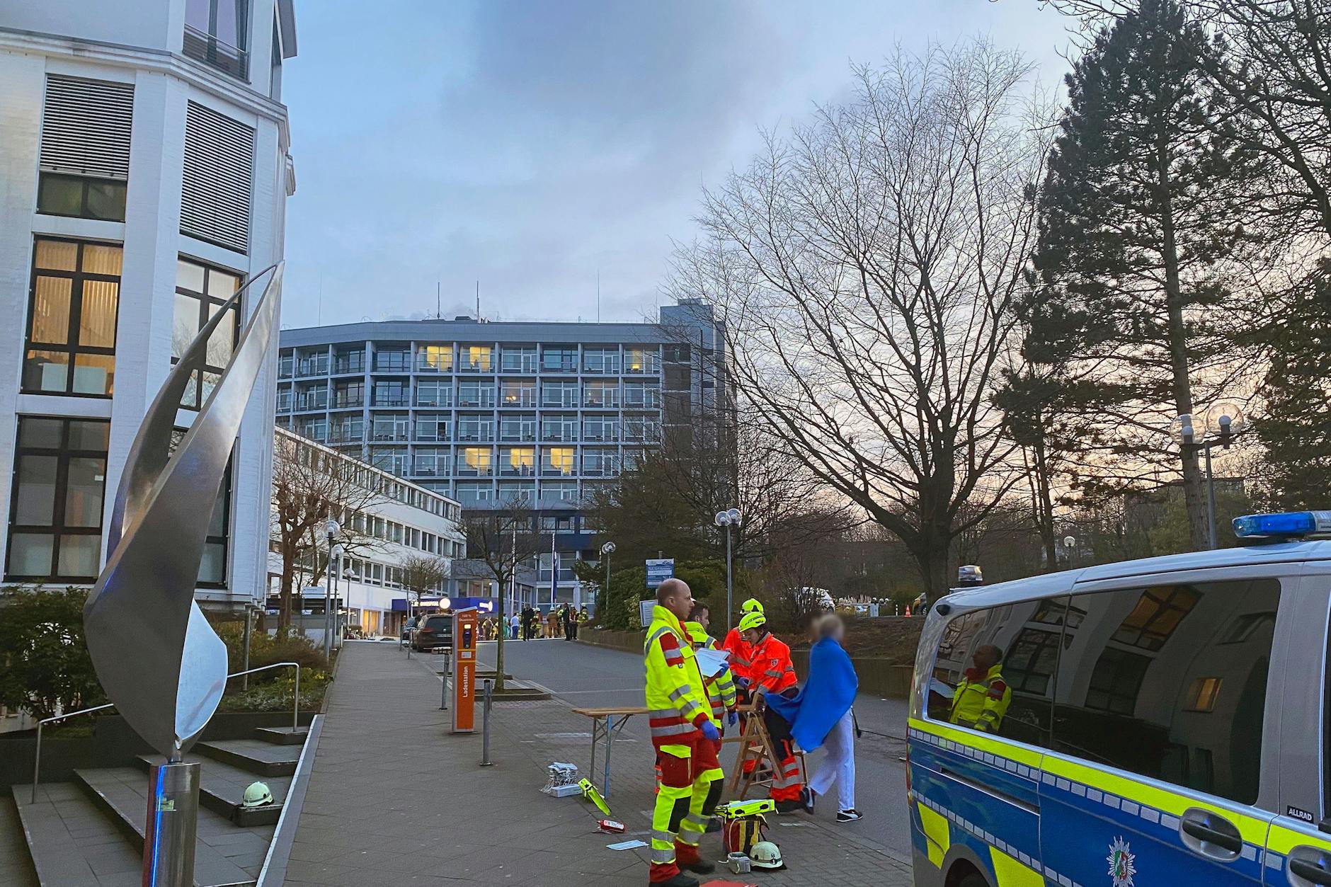Einsatzkräfte von Polizei und Rettungsdienst stehen vor einem Aachener Krankenhaus.