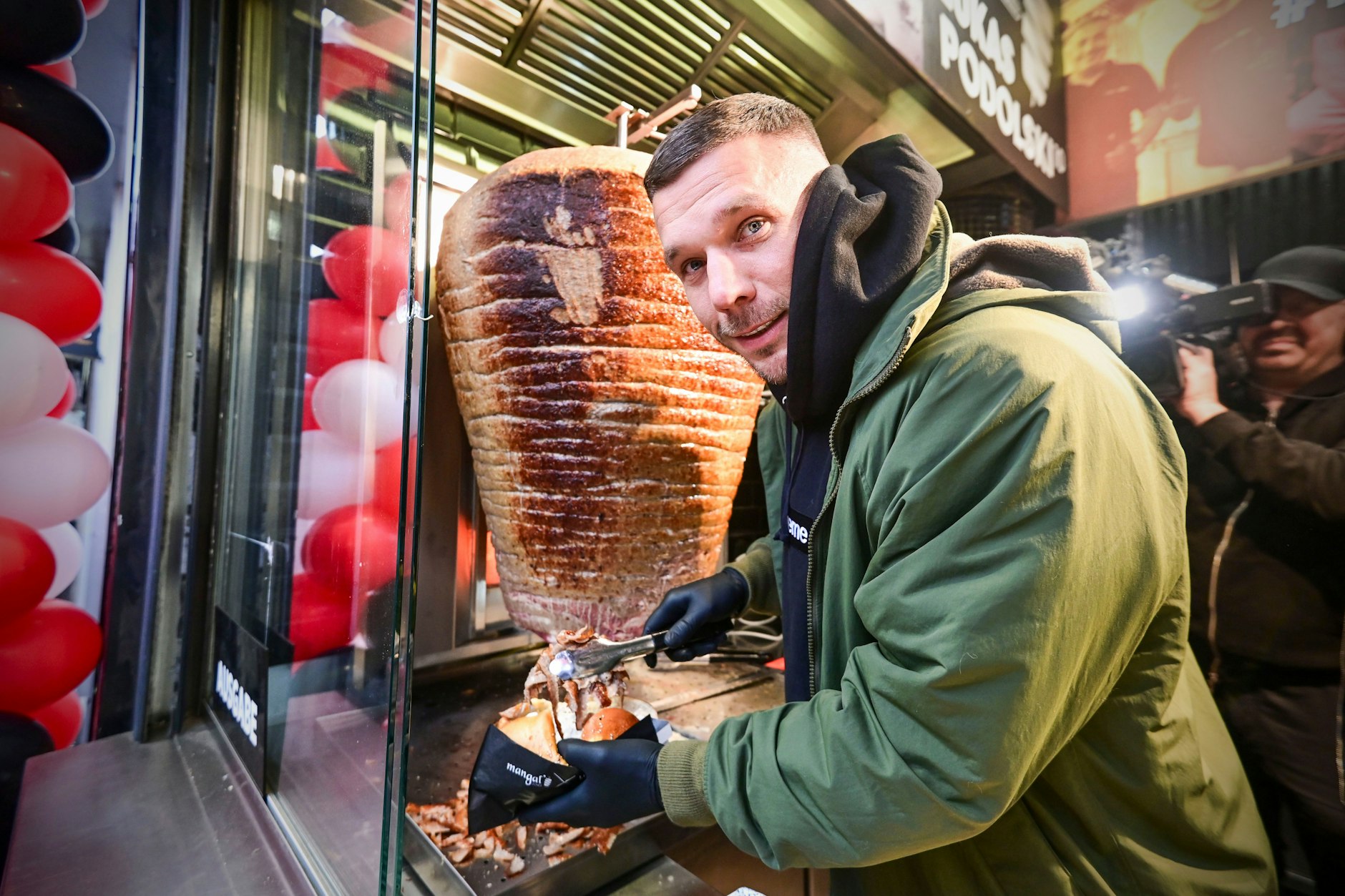 Mit Soße? Hier schneidet der Chef noch selbst: Lukas Podolski bei der Eröffnung seiner Mangal-Filiale am Wochenende in Kreuzberg.